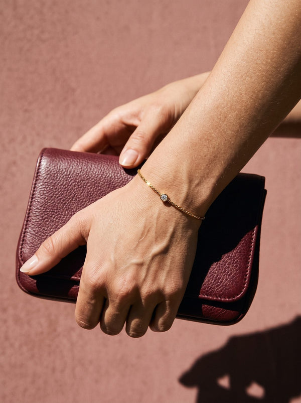 Lundholm Anah armband om een pols met een bordeauxrood avondtasje