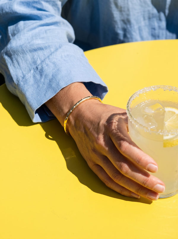 Lundholm Aster zirkonia cuff bangle om een pols bij een glas limonade
