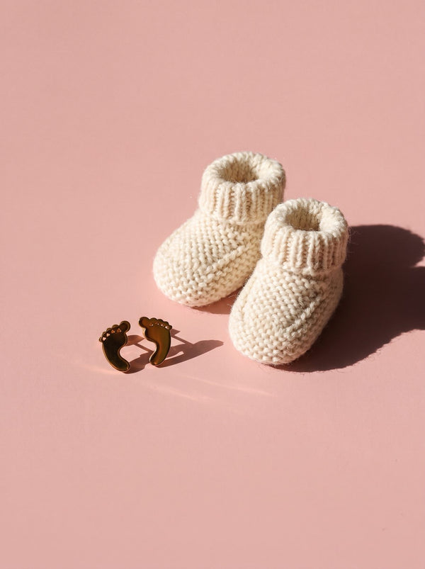 Lundholm Bebe babyvoetjes oorknopjes naast gebreide babyslofjes