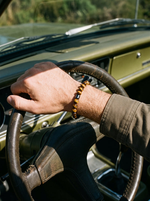 Man draagt de Lundholm Gunnar herenarmband met tijgeroog kralen aan het stuur van een klassieke auto