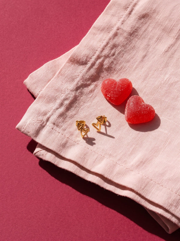 Lundholm Livy dubbele hartjes oorknopjes goudkleurig op roze linnen met snoephartjes