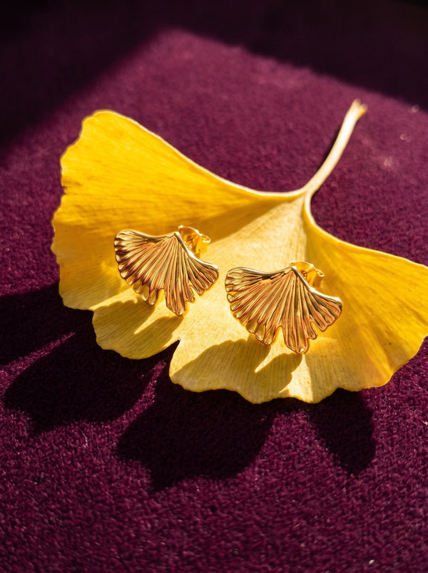 Lundholm Tyra ginkgo oorknopjes goudkleurig op een geel herfstblad op pruimkleurig fluweel