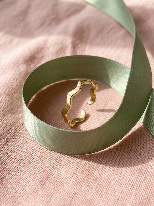 Lundholm Zia verstelbare zigzag ring goudkleurig in een saliegroen satijnen lint op roze linnen