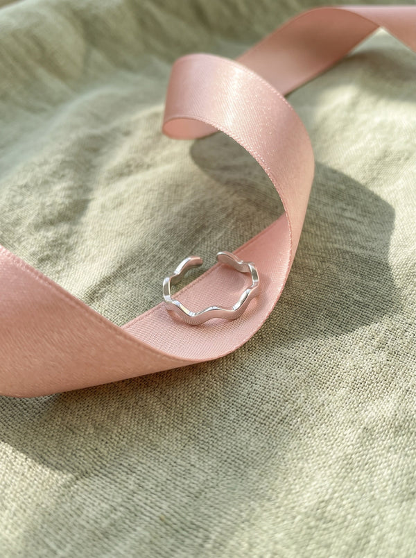 Lundholm Zia zigzag ring zilverkleurig in een roze satijnen lint op saliegroen linnen