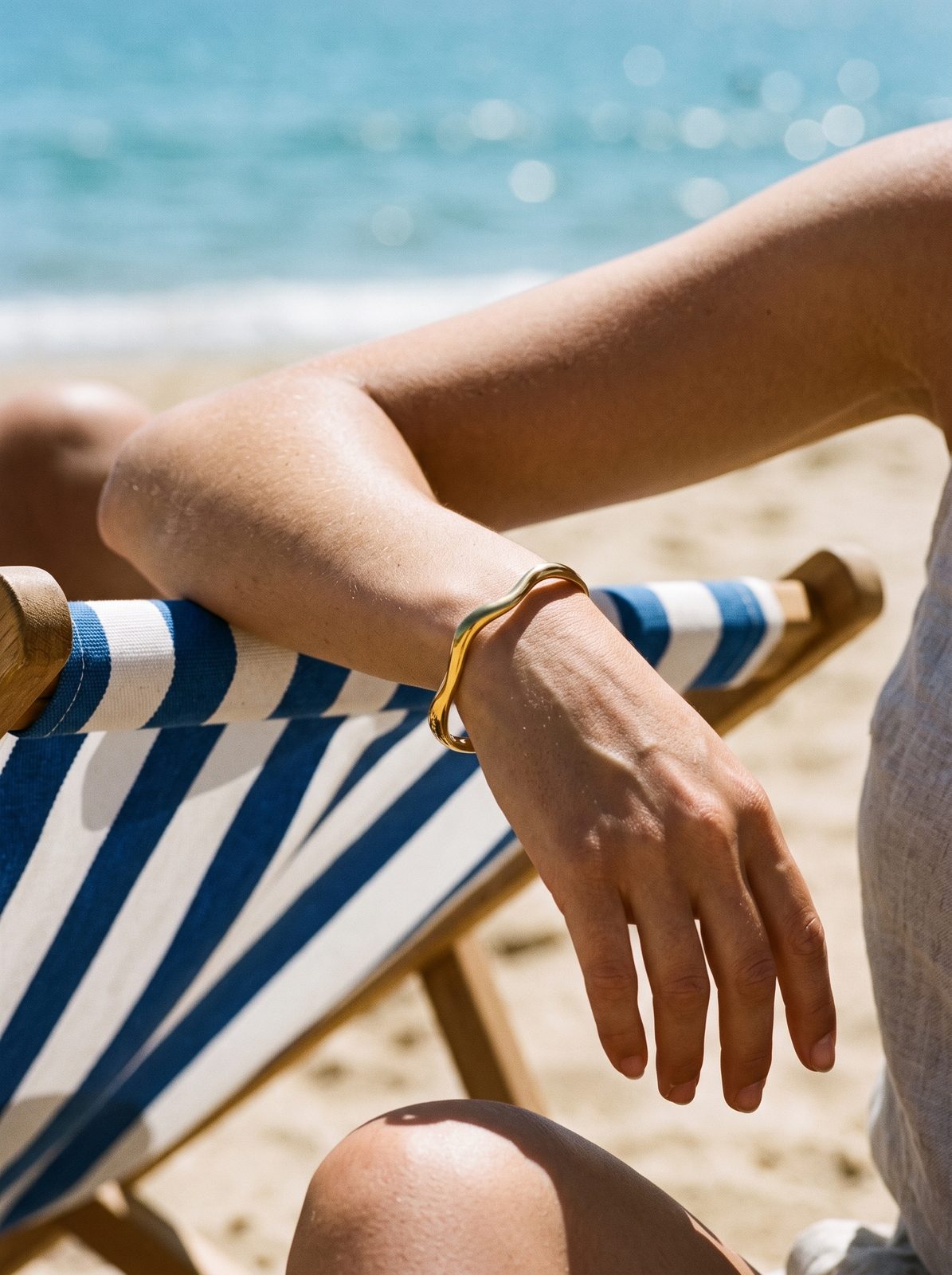 Lundholm Amira statement bangle om een pols op een strandstoel