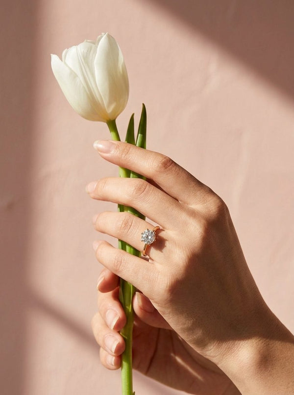 Hand met Lundholm Asta ring houdt een witte tulp vast