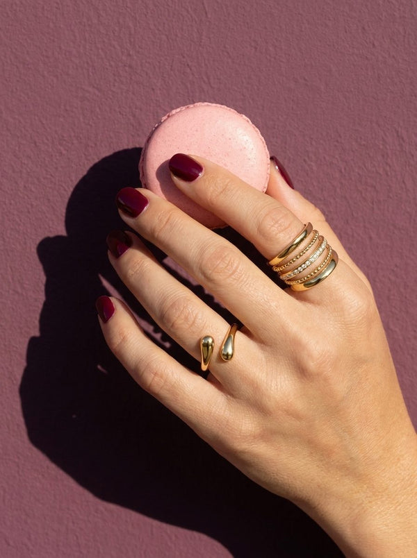 Hand met Lundholm Dagny en Alba ringen houdt een macaron vast