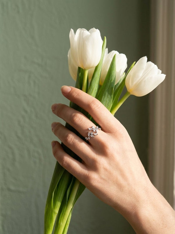 Hand met zilverkleurige Lundholm Sanna ring houdt witte tulpen vast