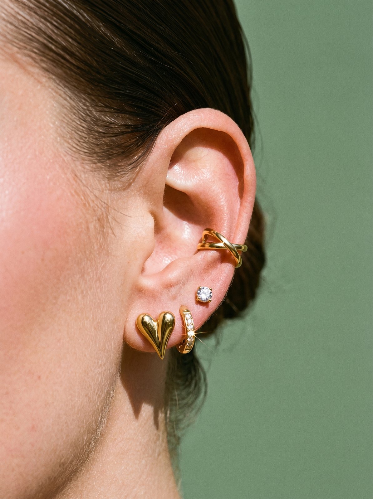 Oor met een goudkleurige ear stack van Lundholm met de Liz earcuff, Delia, Nikki en Inez