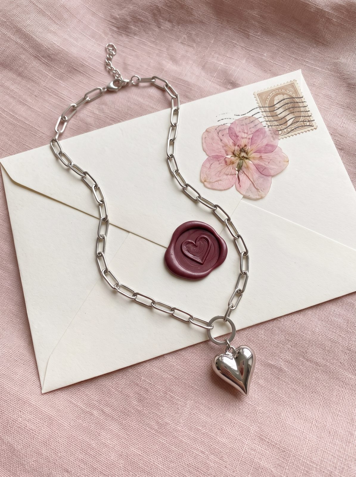 Zilverkleurige hartjesketting op een liefdesbrief met lakzegel