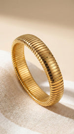 Lundholm Avril Serie elastische stretch statement bangle armband dames goudkleurig one size op linnen achtergrond - waterproof gold plated PVD 2.5 micron premium stainless steel sieraden cadeau vrouw moederdag verjaardag Scandinavisch Design
