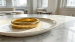 Lundholm Avril Serie elastische stretch statement bangle armband dames goudkleurig op marmeren schaal in licht interieur lifestyle - waterproof gold plated PVD 2.5 micron premium stainless steel sieraden cadeau vrouw moederdag verjaardag Scandinavisch Design
