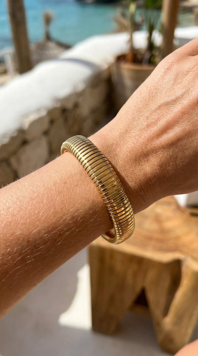 Lundholm Avril Serie elastische stretch statement bangle armband dames goudkleurig gedragen door model op pols lifestyle strand zomer vakantie - waterproof gold plated PVD 2.5 micron premium stainless steel sieraden cadeau vrouw moederdag verjaardag Scandinavisch Design