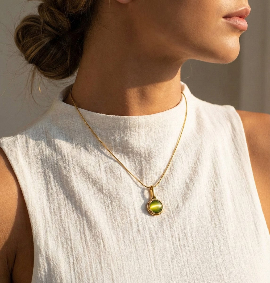 Lundholm Cecile Serie ketting voor dames in goudkleurig met groene natuursteen hanger, gemaakt van premium stainless steel met PVD coating van 2.5 micron, waterproof en hypoallergeen, lifestyle foto van model in witte top, perfect cadeau voor vrouw, moederdag of verjaardag in Scandinavisch design.