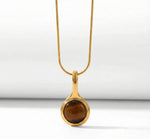 Lundholm Cecile Serie ketting voor dames in goudkleurig met natuurlijke tijgeroog hanger in close-up, gemaakt van premium stainless steel met PVD coating van 2.5 micron, waterproof en hypoallergeen, perfect cadeau voor vrouw, moederdag of verjaardag in Scandinavisch design.