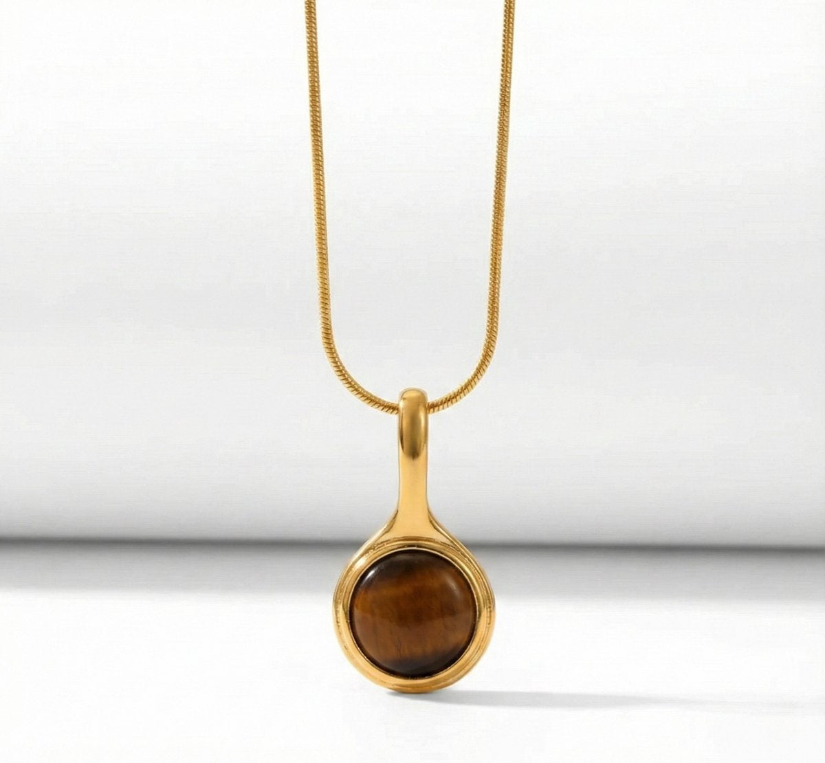Lundholm Cecile Serie ketting voor dames in goudkleurig met natuurlijke tijgeroog hanger in close-up, gemaakt van premium stainless steel met PVD coating van 2.5 micron, waterproof en hypoallergeen, perfect cadeau voor vrouw, moederdag of verjaardag in Scandinavisch design.