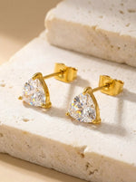 Lundholm Dani goudkleurige driehoek zirkonia oorknopjes dames op crème travertijn steen blok - waterproof gold plated PVD premium stainless steel sieraden cadeau vrouw moederdag verjaardag Scandinavisch Design