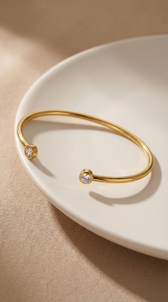 Lundholm Fem Serie open bangle cuff armband dames goudkleurig met zirkonia steentjes op crème keramische schaal lifestyle - waterproof gold plated PVD 2.5 micron premium stainless steel sieraden cadeau vrouw moederdag verjaardag Scandinavisch Design