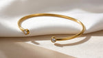 Lundholm Fem Serie open bangle cuff armband dames goudkleurig met zirkonia steentjes op cream stof productfoto - waterproof gold plated PVD 2.5 micron premium stainless steel sieraden cadeau vrouw moederdag verjaardag Scandinavisch Design