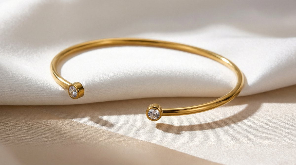 Lundholm Fem Serie open bangle cuff armband dames goudkleurig met zirkonia steentjes op cream stof productfoto - waterproof gold plated PVD 2.5 micron premium stainless steel sieraden cadeau vrouw moederdag verjaardag Scandinavisch Design