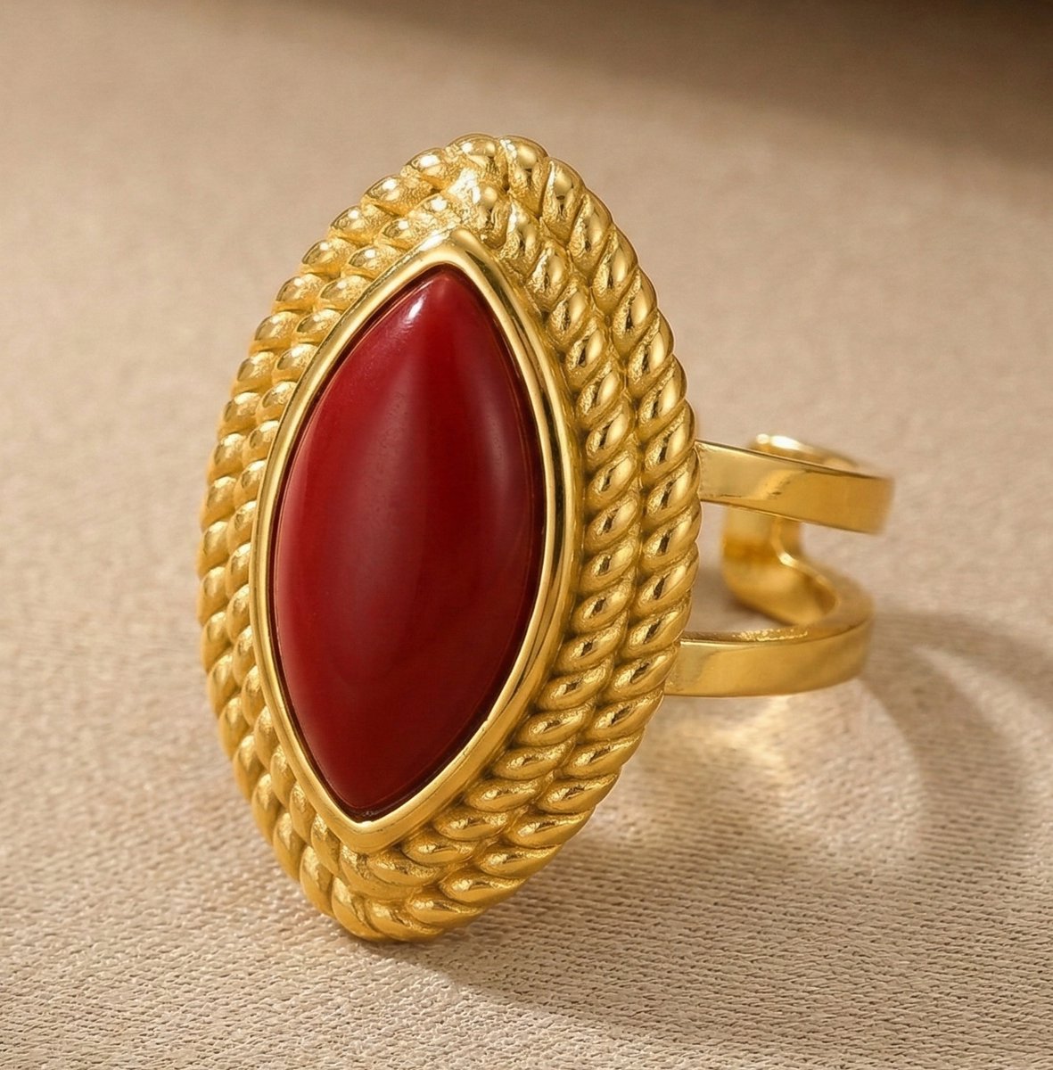 Lundholm Ivana goudkleurige verstelbare statement ring voor dames met grote rode marquise steen omringd door touwpatroon in vintage ontwerp, gefotografeerd close-up op crème ondergrond voor luxe productshot. Premium stainless steel met PVD gold plating van 2.5 micron, waterproof en hypoallergeen. Een opvallend cadeau voor vrouw, moeder of vriendin op Moederdag of verjaardag in Scandinavisch design.