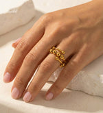 Lundholm Lauren goudkleurige verstelbare anxiety ring voor dames met schuifbare bolletjes voor stress relief en fidget, gedragen door vrouw close-up op natuursteen voor warme lookbook lifestyle shoot. Premium stainless steel met PVD gold plating van 2.5 micron, waterproof en hypoallergeen. Een doordacht cadeau voor vrouw, moeder of vriendin op Moederdag of verjaardag in Scandinavisch design.