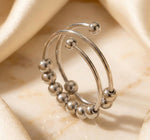 Lundholm Lauren zilverkleurige verstelbare anxiety ring voor dames met schuifbare bolletjes en spiraal ontwerp voor stress relief en fidget, gefotografeerd op crème zijde voor luxe productshot. Premium stainless steel met PVD silver plating, waterproof en hypoallergeen. Een doordacht cadeau voor vrouw, moeder of vriendin op Moederdag of verjaardag in Scandinavisch design.