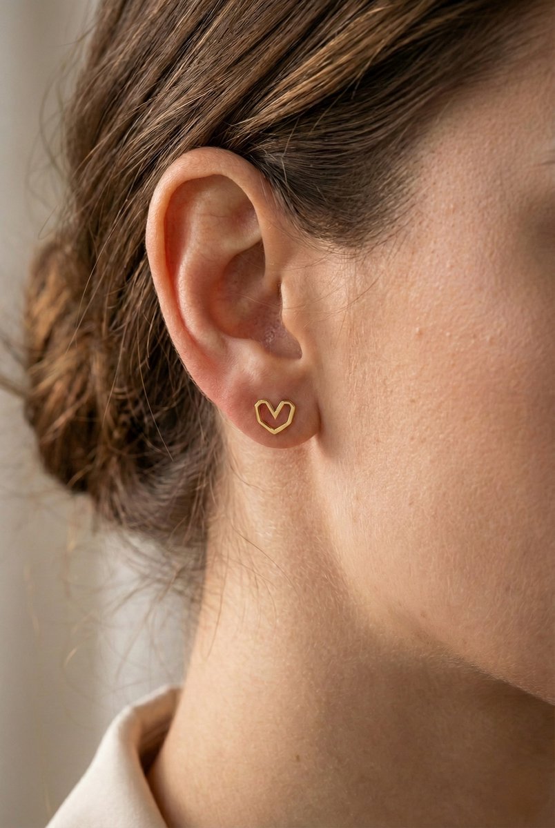 Lundholm Liza goudkleurige hartje oorbellen voor dames met minimalistisch open hart ontwerp, gedragen door vrouw voor close-up lookbook shoot. Premium stainless steel met PVD gold plating van 2.5 micron, waterproof en hypoallergeen. Het ideale cadeau voor vrouw, moeder of vriendin op Moederdag of verjaardag in subtiel Scandinavisch design.