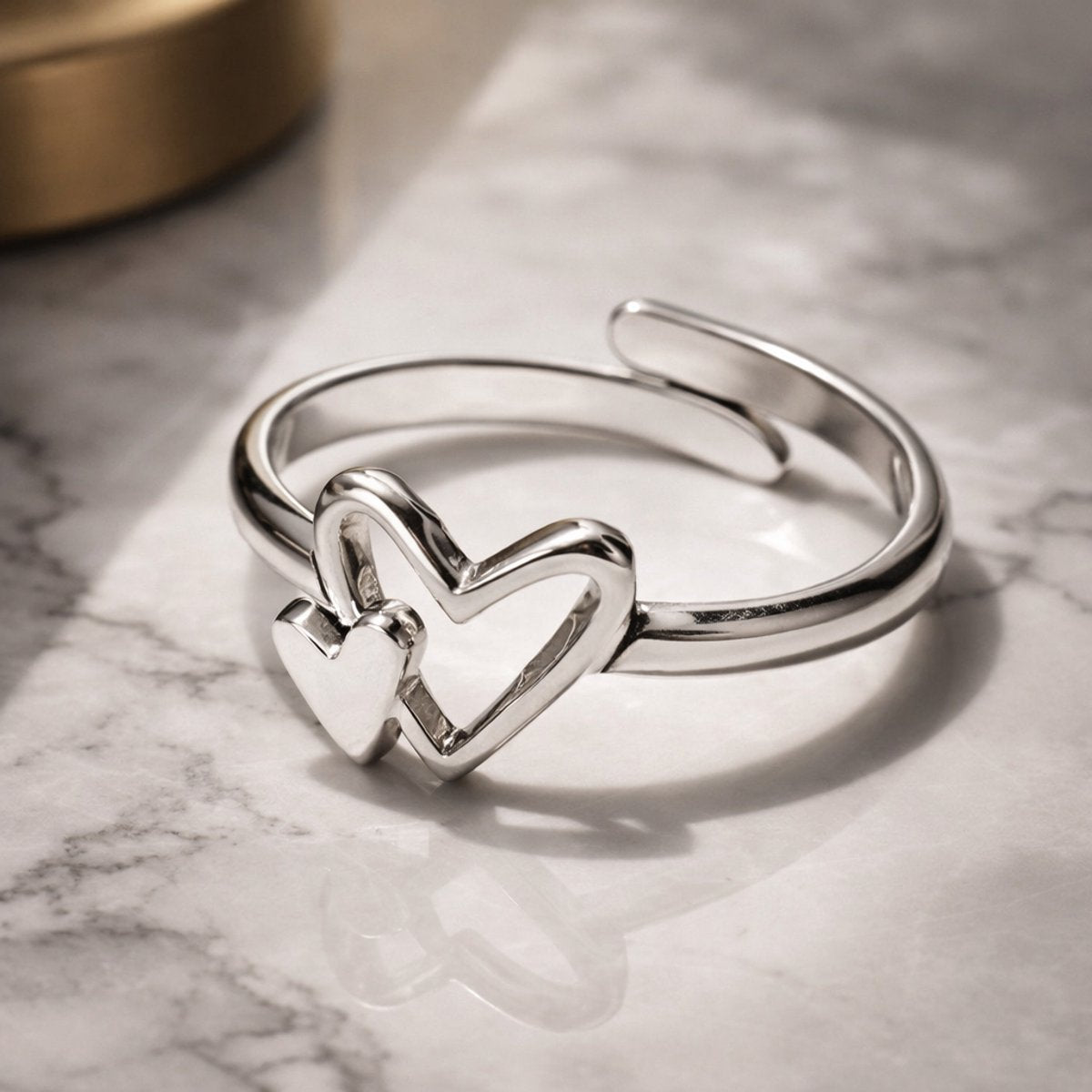 Lundholm Ljuv verstelbare zilverkleurige ring voor dames met dubbel hartje ontwerp, gefotografeerd op een marmeren oppervlak. Premium stainless steel met PVD silver plating, waterproof en hypoallergeen. Het perfecte cadeau voor vrouw, moeder of vriendin op Moederdag of verjaardag in tijdloos Scandinavisch design.