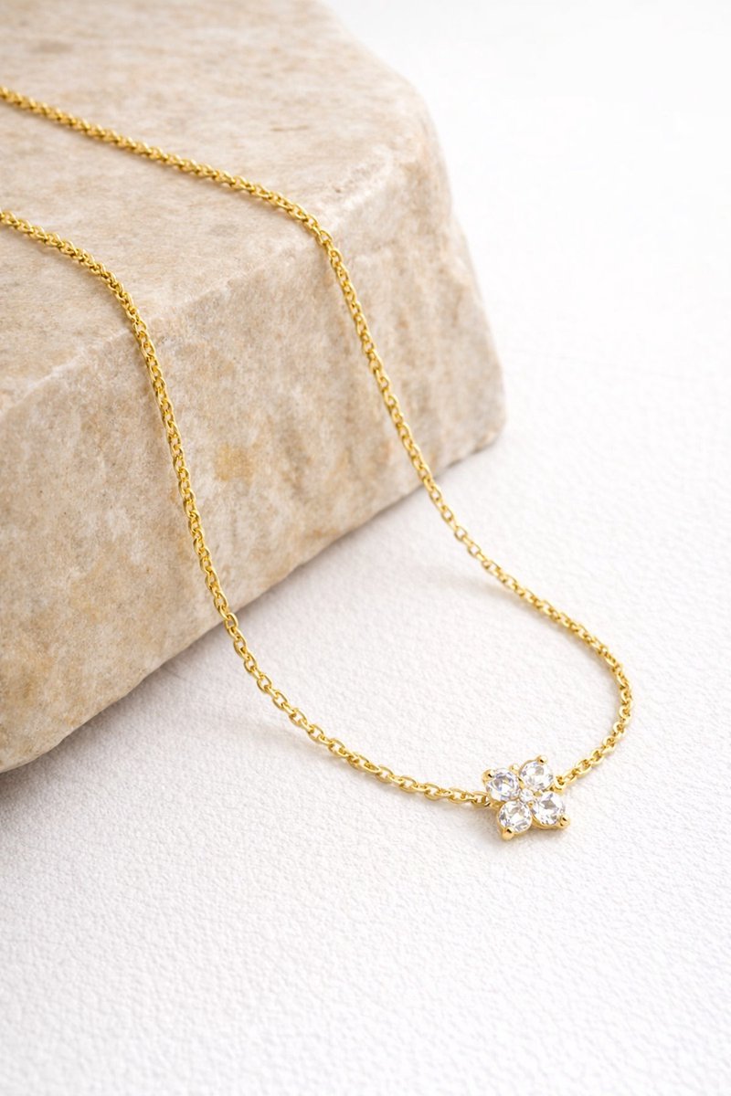 Lundholm Lukk goudkleurige geluksketting voor dames met klavertje vier hanger ingelegd met fonkelende zirkonia, gefotografeerd op natuursteen voor stijlvolle productshot. Premium stainless steel met PVD gold plating van 2.5 micron, waterproof en hypoallergeen. Een betekenisvol cadeau voor vrouw, moeder of vriendin op Moederdag of verjaardag in Scandinavisch design.