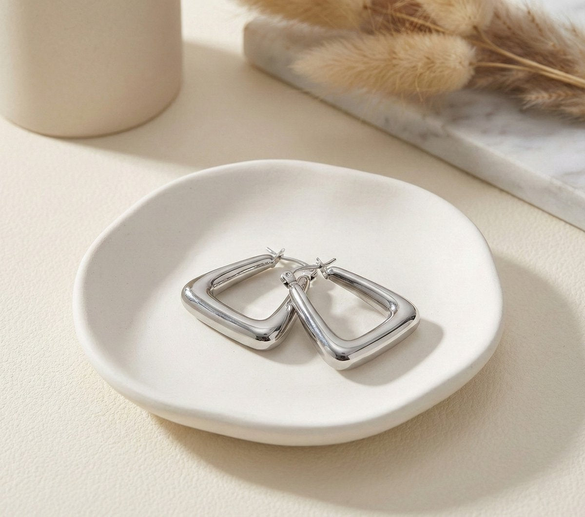 Lundholm Lymee Serie luxe oorbellen voor dames in zilverkleurig met chunky design in witte keramische schaal met droogbloemen, gemaakt van premium stainless steel met PVD coating, waterproof en hypoallergeen, perfect cadeau voor vrouw, moederdag of verjaardag in Scandinavisch design.
