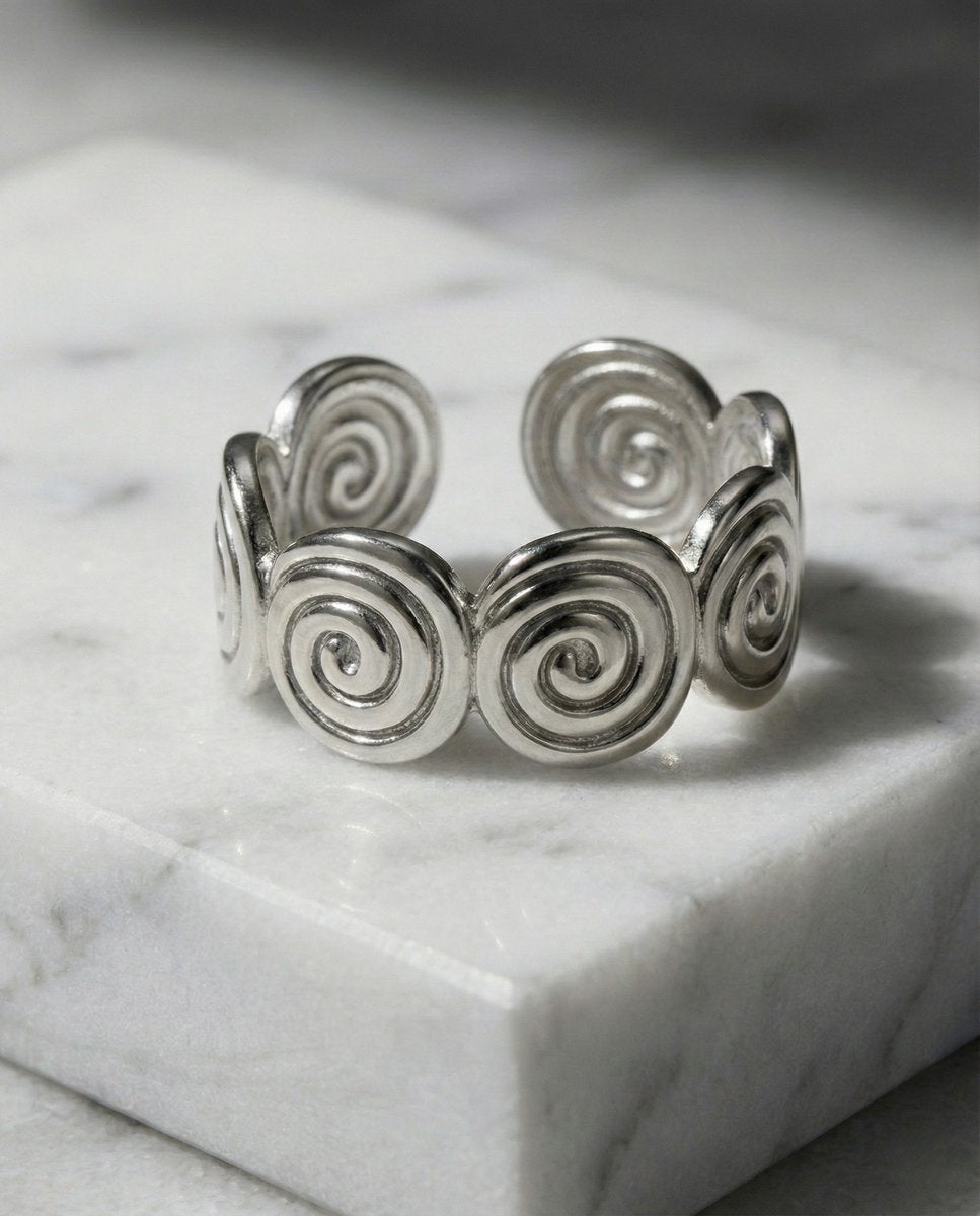 Lundholm Merel zilverkleurige verstelbare ring voor dames met aesthetic spiraal swirl ontwerp, gefotografeerd op witte marmeren ondergrond voor stijlvolle productshot. Premium stainless steel met PVD silver plating, waterproof en hypoallergeen. Een unieke cadeau voor vrouw, moeder of vriendin op Moederdag of verjaardag in Scandinavisch design.