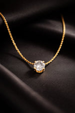 Lundholm Monique goudkleurige minimalistische ketting voor dames met fonkelende solitaire zirkonia steen hanger, gefotografeerd op zwart fluweel voor luxe productshot. Premium stainless steel met PVD gold plating van 2.5 micron, waterproof en hypoallergeen. Een tijdloos cadeau voor vrouw, moeder of vriendin op Moederdag of verjaardag in Scandinavisch design.