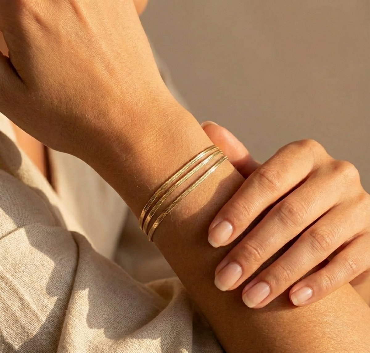 Lundholm My Bibi Serie luxe armband voor dames in goudkleurig met drie laags minimalistisch design gedragen aan pols van model in lifestyle setting, gemaakt van premium stainless steel met PVD coating van 2.5 micron, waterproof en hypoallergeen, perfect cadeau voor vrouw, moederdag of verjaardag in Scandinavisch design.