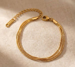 Lundholm My Bibi Serie luxe armband voor dames in goudkleurig met drie laags minimalistisch design op linnen achtergrond, gemaakt van premium stainless steel met PVD coating van 2.5 micron, waterproof en hypoallergeen, perfect cadeau voor vrouw, moederdag of verjaardag in Scandinavisch design.
