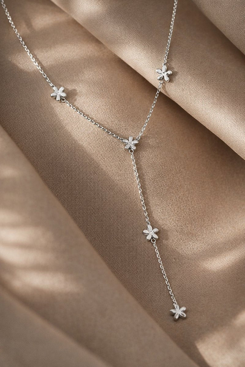 Lundholm My Elora zilverkleurige Y-vormige lariat ketting voor dames met bloemetjes accenten en 44 cm verlengstuk, gefotografeerd op crème zijde voor elegante productshot. Premium stainless steel met PVD silver plating, waterproof en hypoallergeen. Een vrouwelijk cadeau voor vrouw, moeder of vriendin op Moederdag of verjaardag in Scandinavisch design.