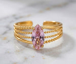Lundholm My Juliette goudkleurige verstelbare cuff ring voor dames met grote roze marquise natuursteen op gestippelde band, gefotografeerd op witte marmeren ondergrond voor luxe productshot. Premium stainless steel met PVD gold plating van 2.5 micron, waterproof en hypoallergeen. Een romantisch cadeau voor vrouw, moeder of vriendin op Moederdag of verjaardag in Scandinavisch design.