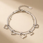 Lundholm My Liv Serie dubbele laags schakelarmband dames zilverkleurig met hartje hangers en bolletjes op zandkleurige achtergrond - waterproof premium stainless steel sieraden cadeau vrouw moederdag verjaardag Scandinavisch Design