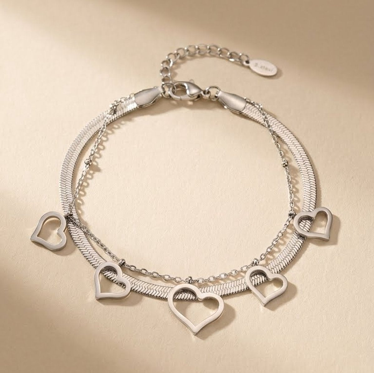Lundholm My Liv Serie dubbele laags schakelarmband dames zilverkleurig met hartje hangers en bolletjes op zandkleurige achtergrond - waterproof premium stainless steel sieraden cadeau vrouw moederdag verjaardag Scandinavisch Design