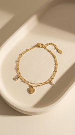 Lundholm My Lizzy Serie dubbel laags bedel armband dames goudkleurig met hartje en zirkonia charm op crème keramische schaal - waterproof gold plated PVD premium stainless steel sieraden cadeau vrouw moederdag verjaardag Scandinavisch Design