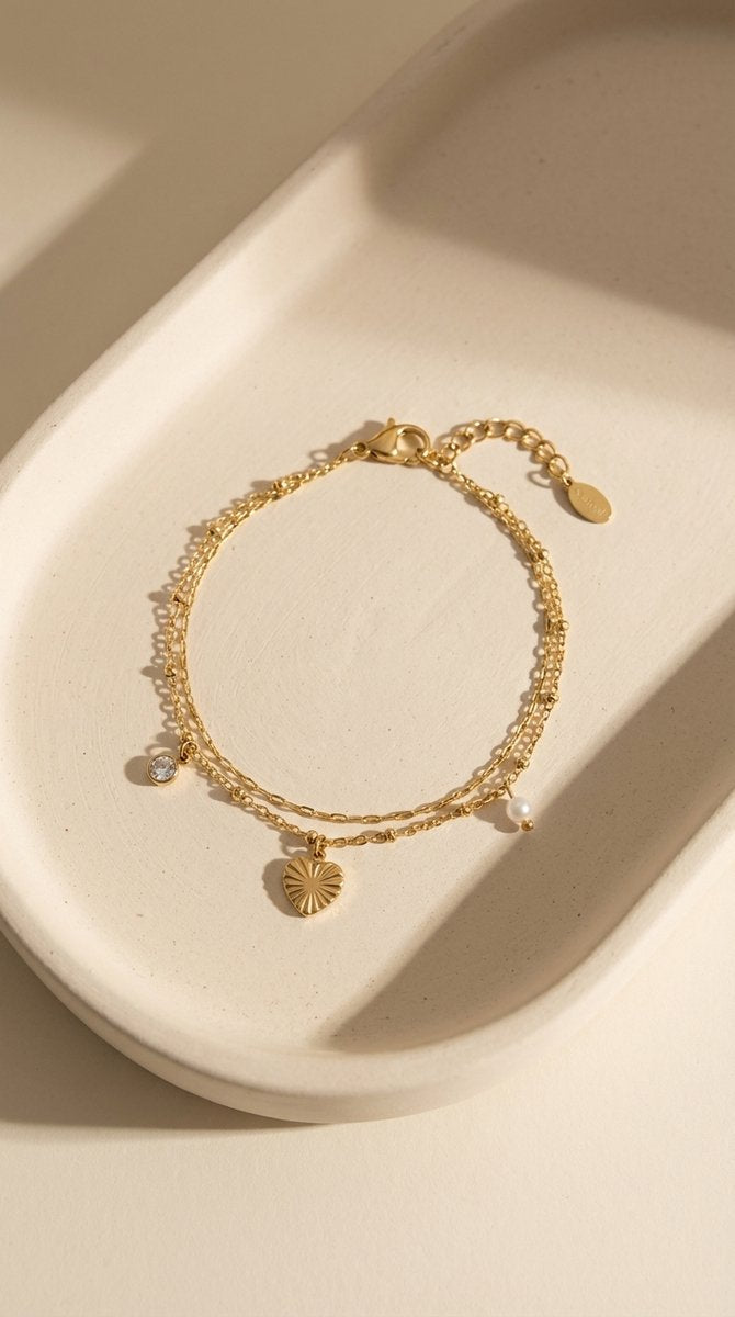 Lundholm My Lizzy Serie dubbel laags bedel armband dames goudkleurig met hartje en zirkonia charm op crème keramische schaal - waterproof gold plated PVD premium stainless steel sieraden cadeau vrouw moederdag verjaardag Scandinavisch Design