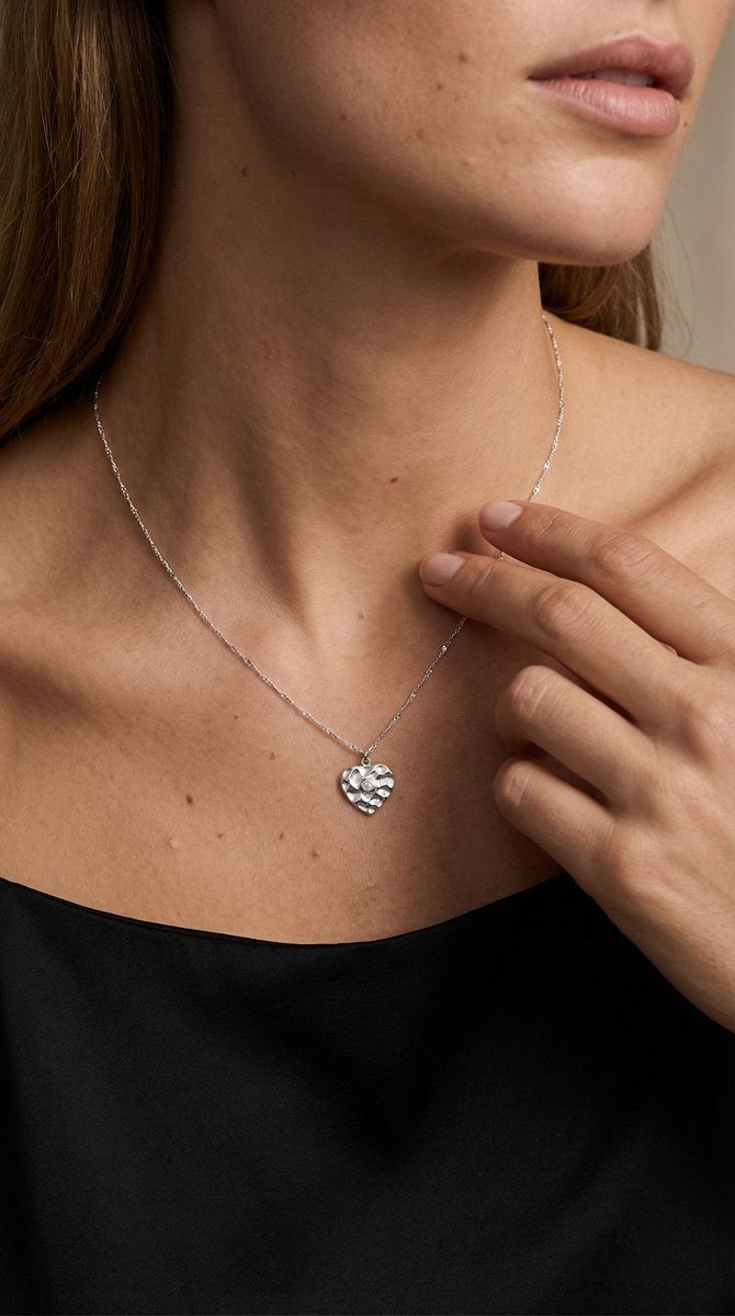 Lundholm My Monica Serie ketting dames zilverkleurig met gehamerd hartje hanger gedragen door model in zwart top lifestyle - waterproof premium stainless steel sieraden cadeau vrouw moederdag verjaardag Scandinavisch Design
