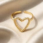 Lundholm My Rae goudkleurige verstelbare statement ring voor dames met open hart ontwerp en getwiste touw textuur, gefotografeerd op crème zijde voor stijlvolle productshot. Premium stainless steel met PVD gold plating van 2.5 micron, waterproof en hypoallergeen. Een romantisch cadeau voor vrouw, moeder of vriendin op Moederdag of verjaardag in Scandinavisch design.
