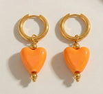 Lundholm Neeltje goudkleurige huggie oorbellen voor dames met grote oranje hartjes hangers van 4 cm, perfect voor Koningsdag accessoires en feestelijke gelegenheden. Premium stainless steel met PVD gold plating van 2.5 micron, waterproof en hypoallergeen. Een vrolijk cadeau voor vrouw, moeder of vriendin op Koningsdag, Moederdag of verjaardag in Scandinavisch design.