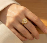 Lundholm Ophelia Serie luxe ring voor dames in goudkleurig met bloemvormige zirkonia 360 graden draaibare statement ring gedragen aan hand van model in lifestyle setting, gemaakt van premium stainless steel met PVD coating van 2.5 micron, waterproof en hypoallergeen, perfect cadeau voor vrouw, moederdag of verjaardag in Scandinavisch design.
