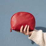 Lundholm make-up tasje rood van nappaleer in de hand, tegen een stoffig blauwe muur
