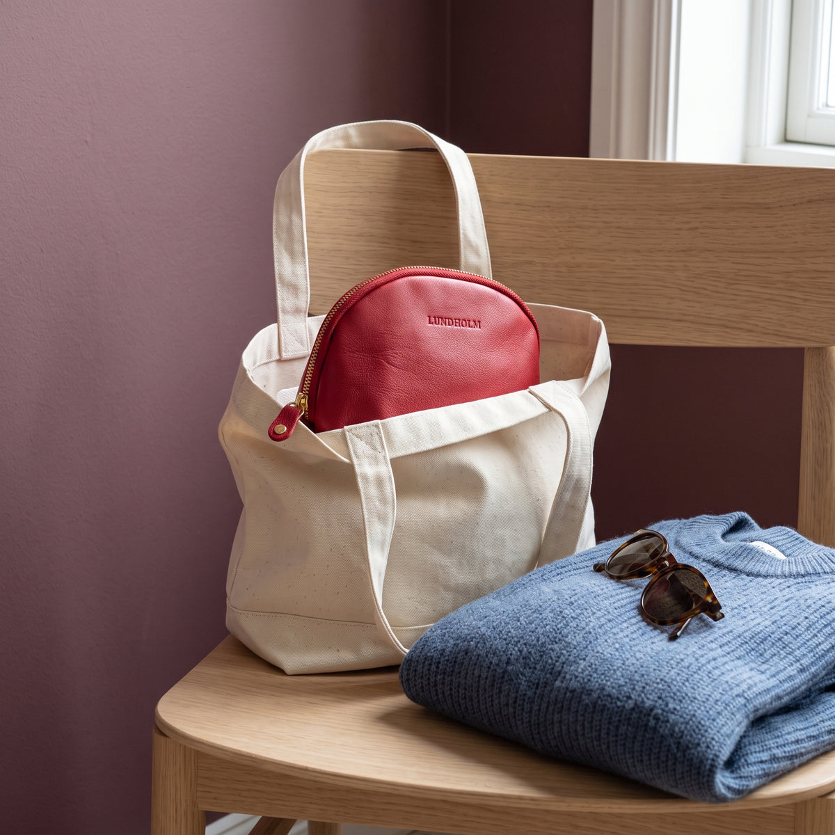 Lundholm make-up tasje rood als bag-in-bag in een canvas shopper op een houten stoel