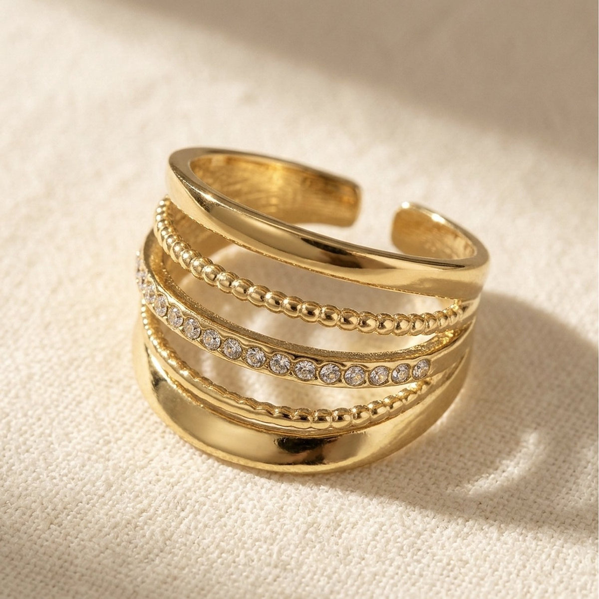 Close-up van de gladde banden, bolletjesranden en steentjes van de Lundholm Alba ring goud