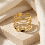 Lundholm Alba goudkleurige ring met vijf lagen en een rij glinsterende steentjes op natuursteen