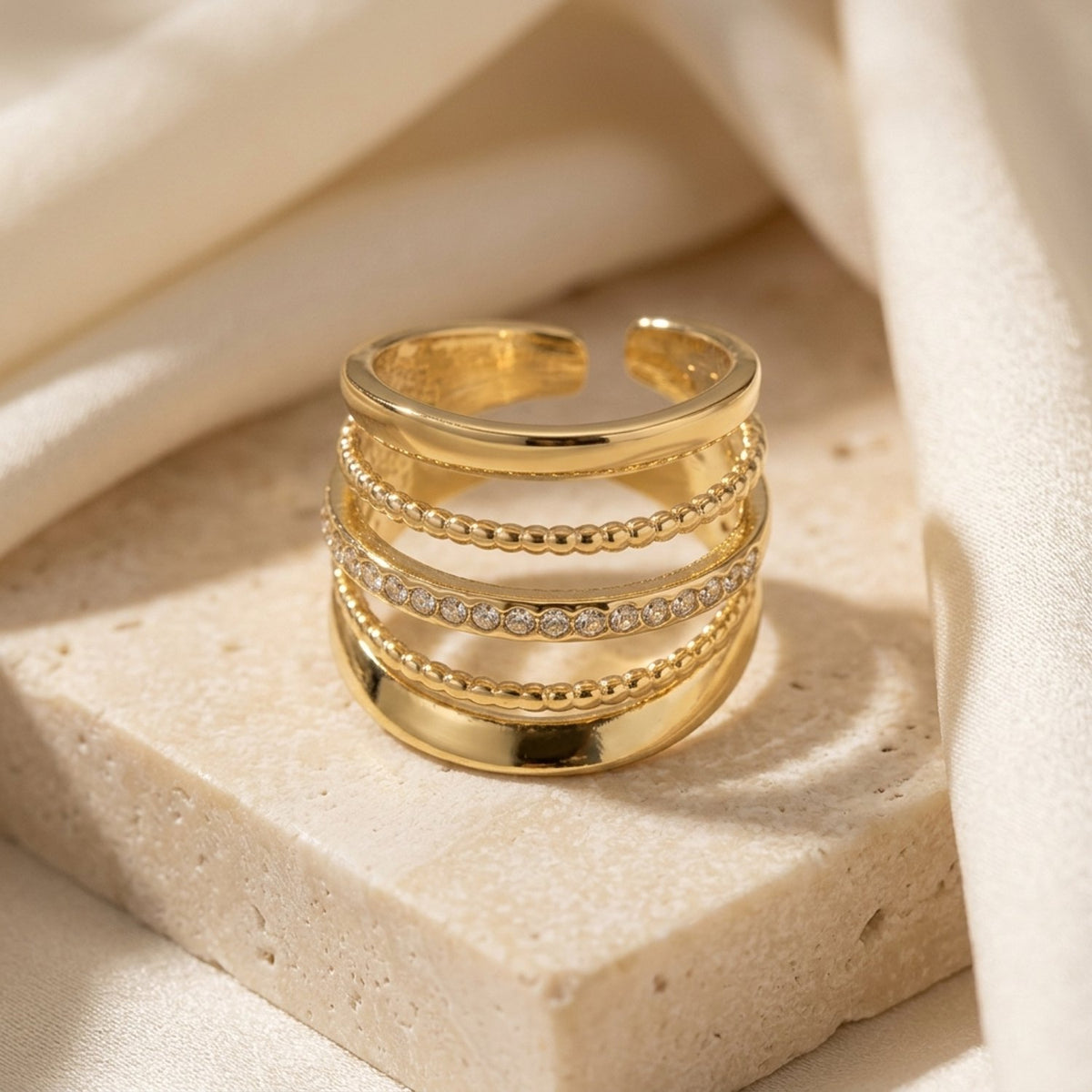 Lundholm Alba goudkleurige ring met vijf lagen en een rij glinsterende steentjes op natuursteen